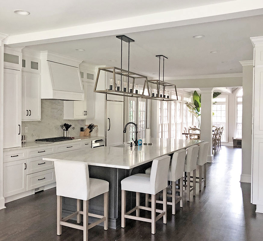Modern white kitchen with island and high stools.